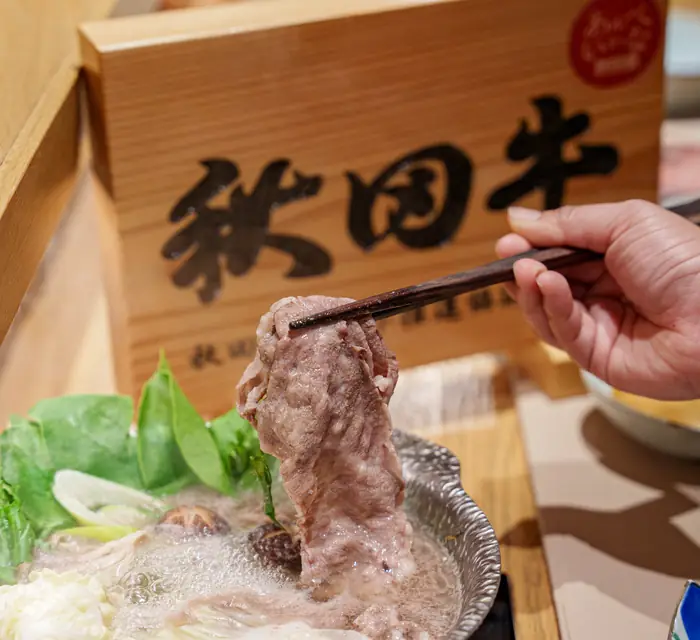 คีบเนื้อวากิวลวกในหม้อชาบู ข้างป้ายไม้ 秋田牛